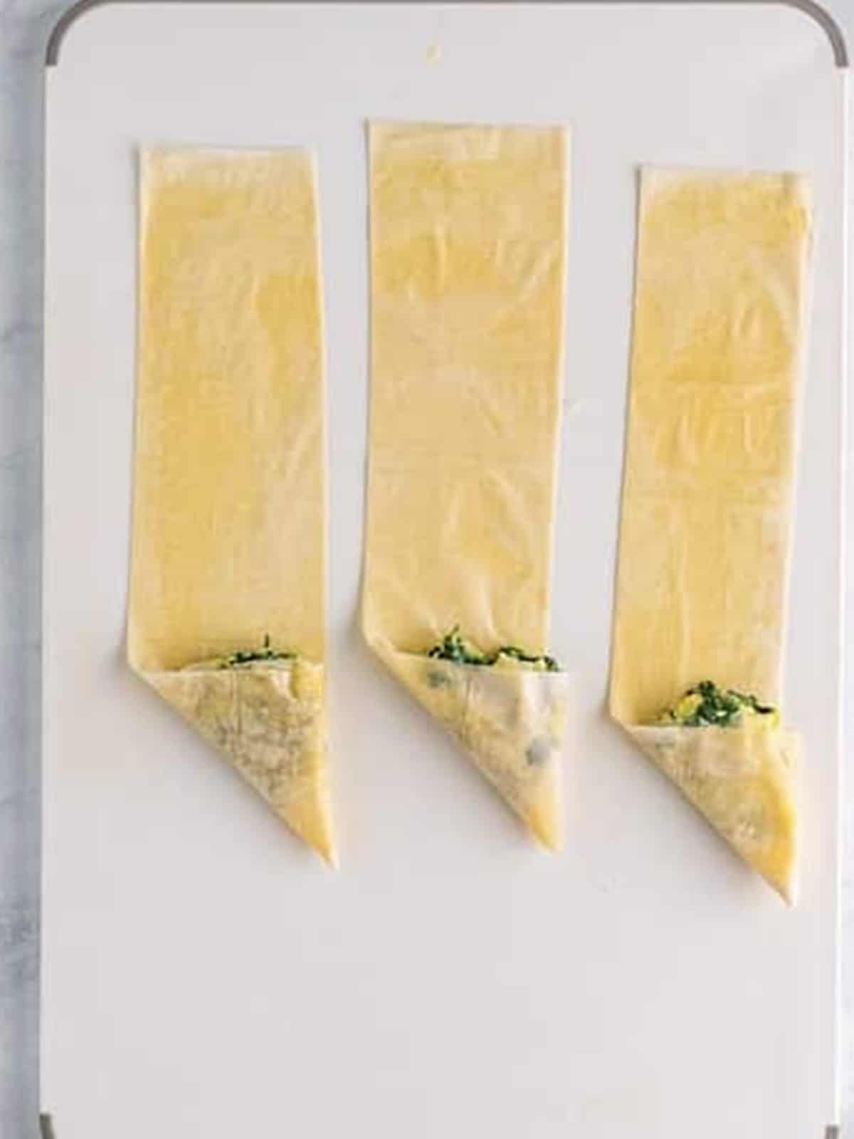 Phyllo folded over the filling into spanakopita triangles.