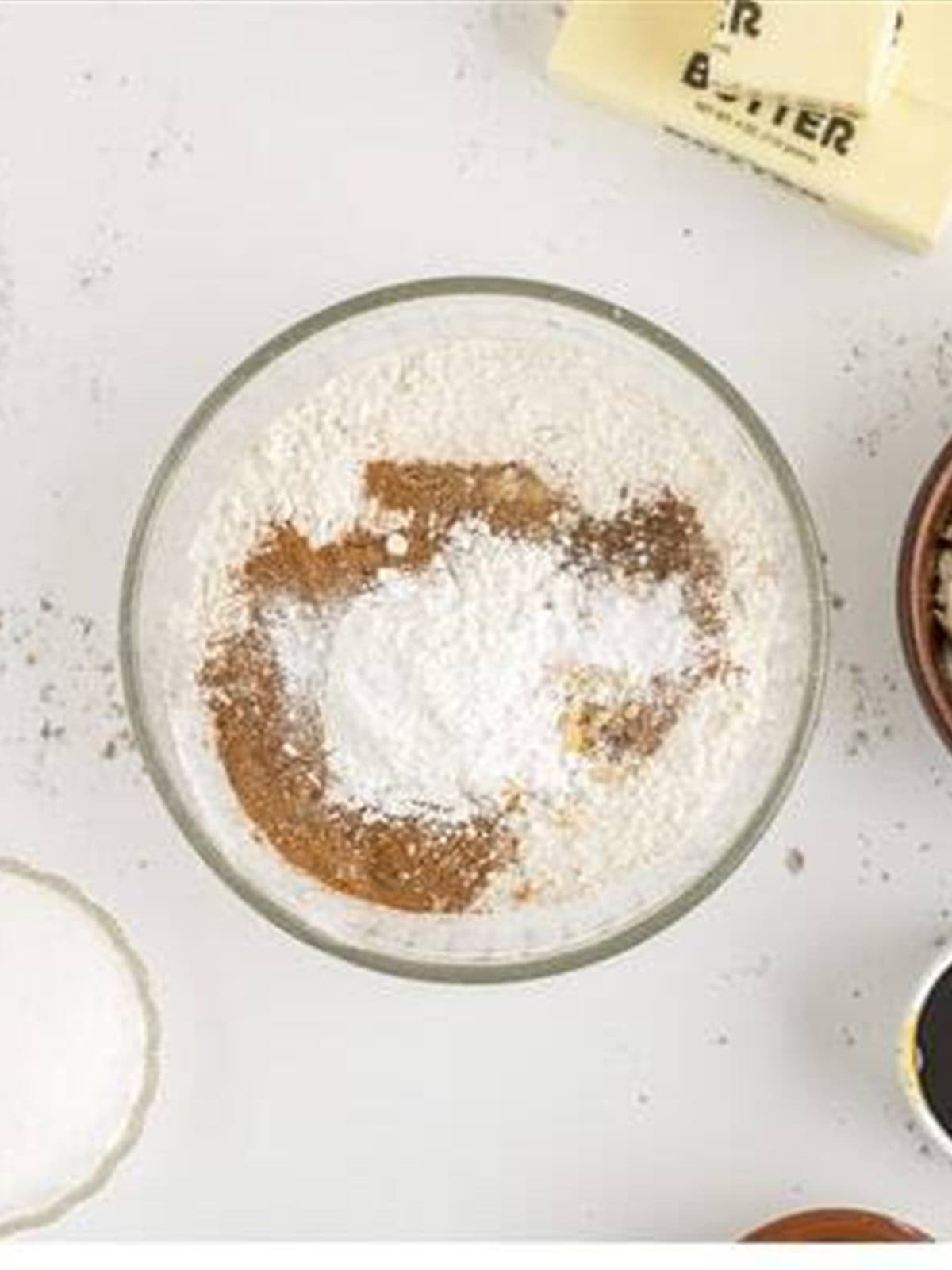 Flour and warm spices whisked together in a bowl for spice cookies.