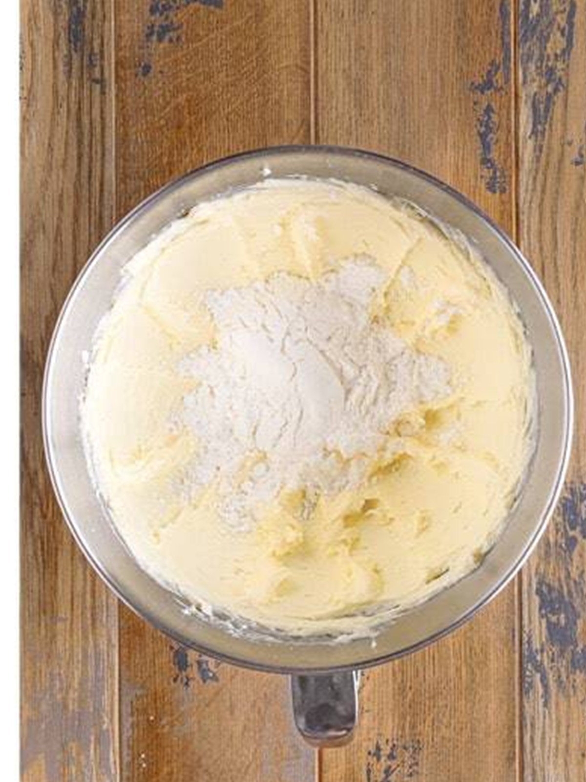 Powdered sugar added to the cream cheese frosting in a mixer.