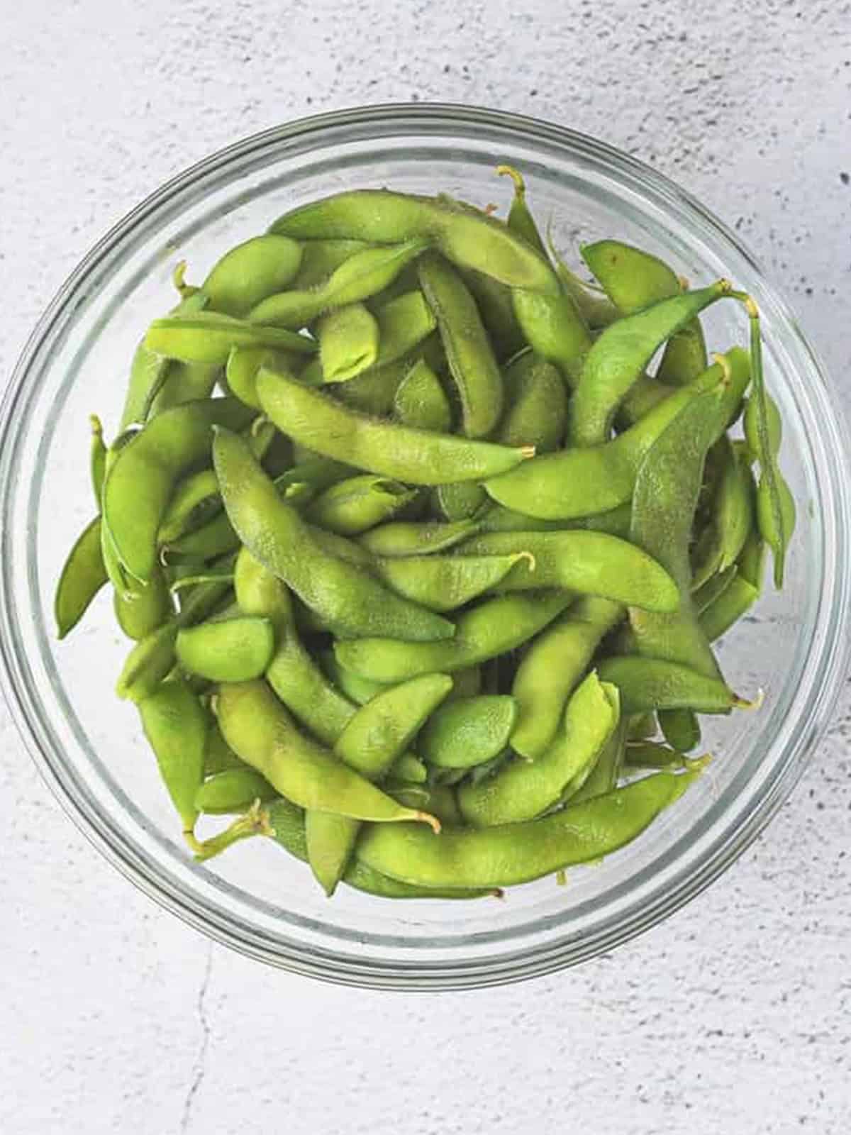 Boiled edamame in a glass bowl ready for the edamame recipe.