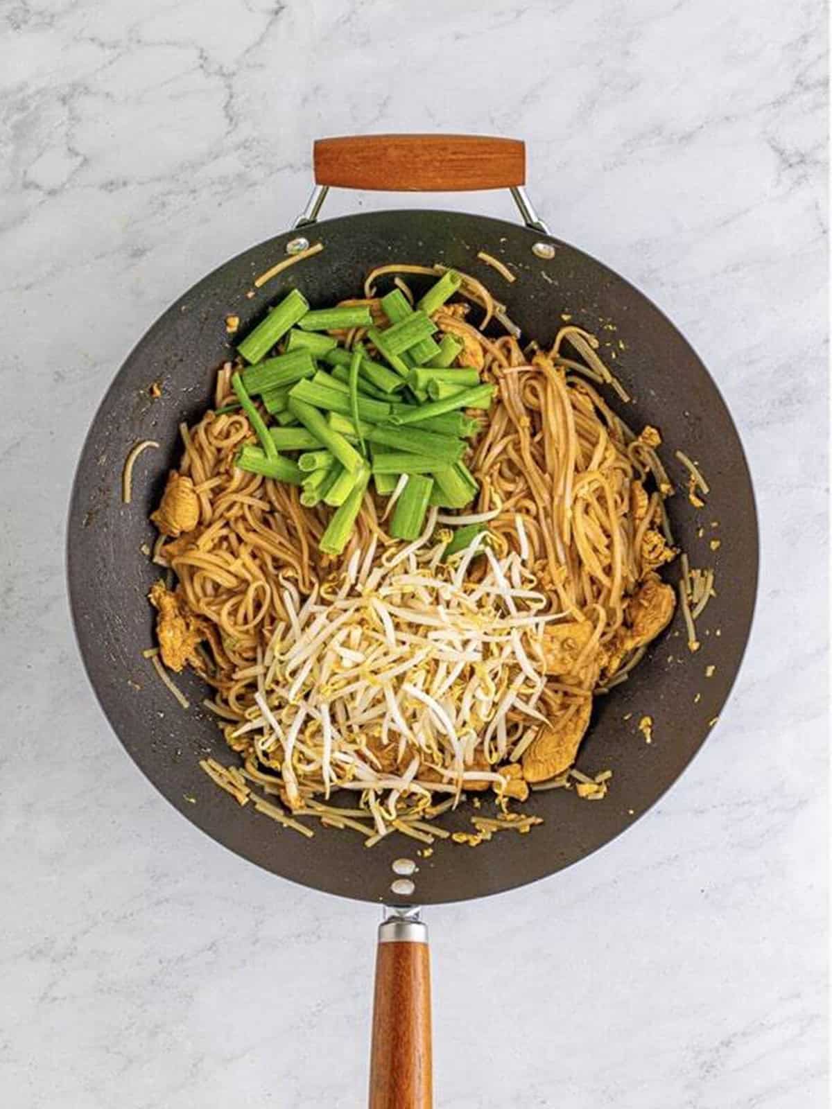 Green onions and fresh bean sprouts added on top of the saucy noodles.