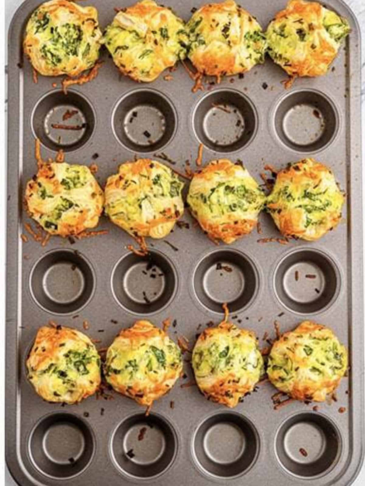 Golden baked spinach puffs in a mini muffin tin.