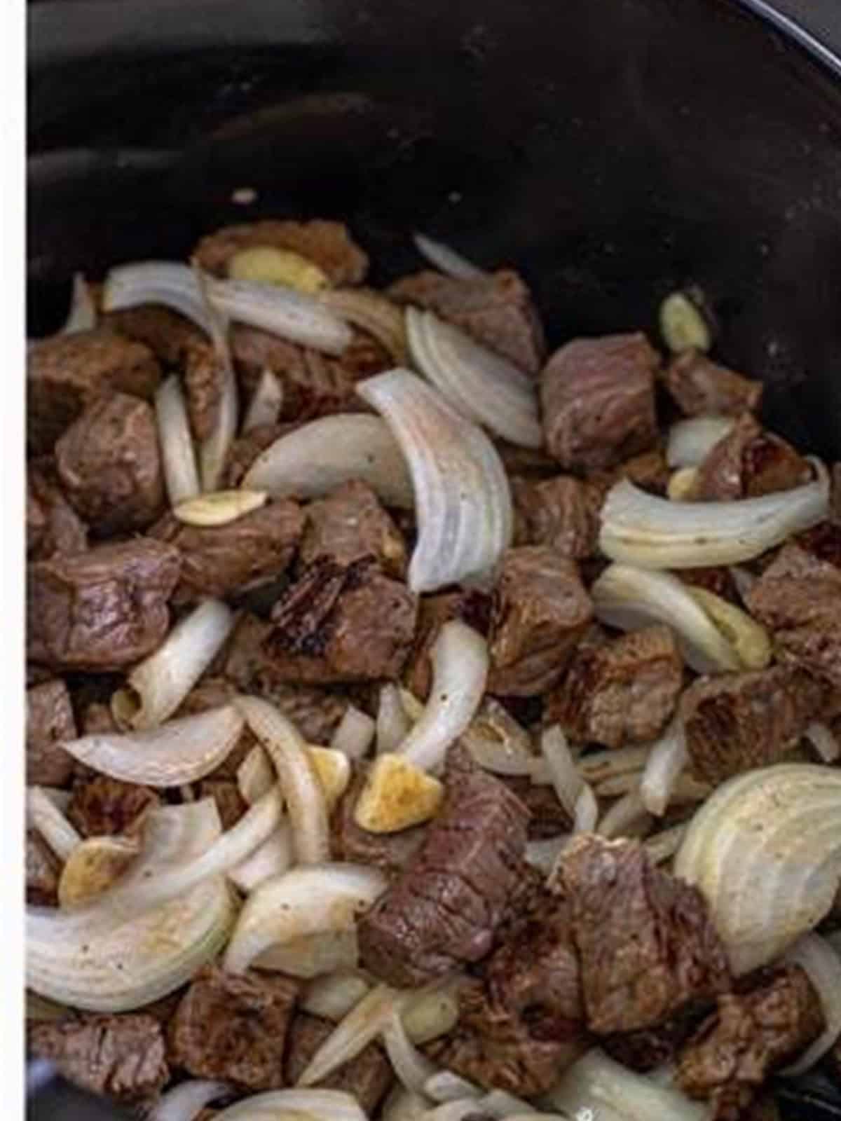Sliced onion and garlic added to the seared steak bites.