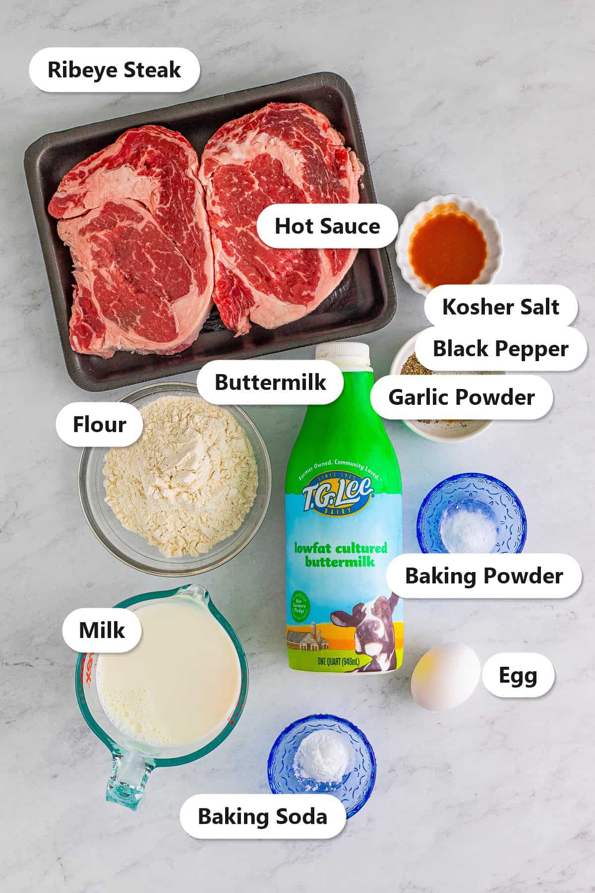 Labeled ingredients for chicken fried steak fingers including ribeye steak, kosher salt, black pepper, garlic powder, hot sauce, flour, buttermilk, baking powder, baking soda, milk, and egg.