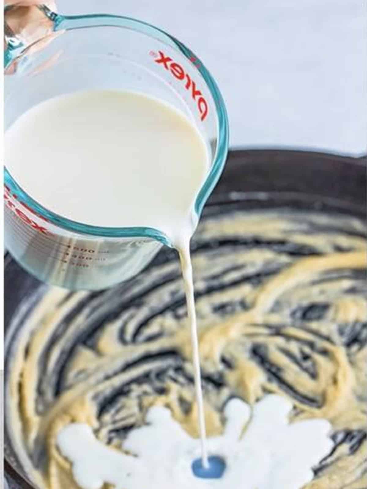 Whole milk streamed into the roux while whisking to make gravy.