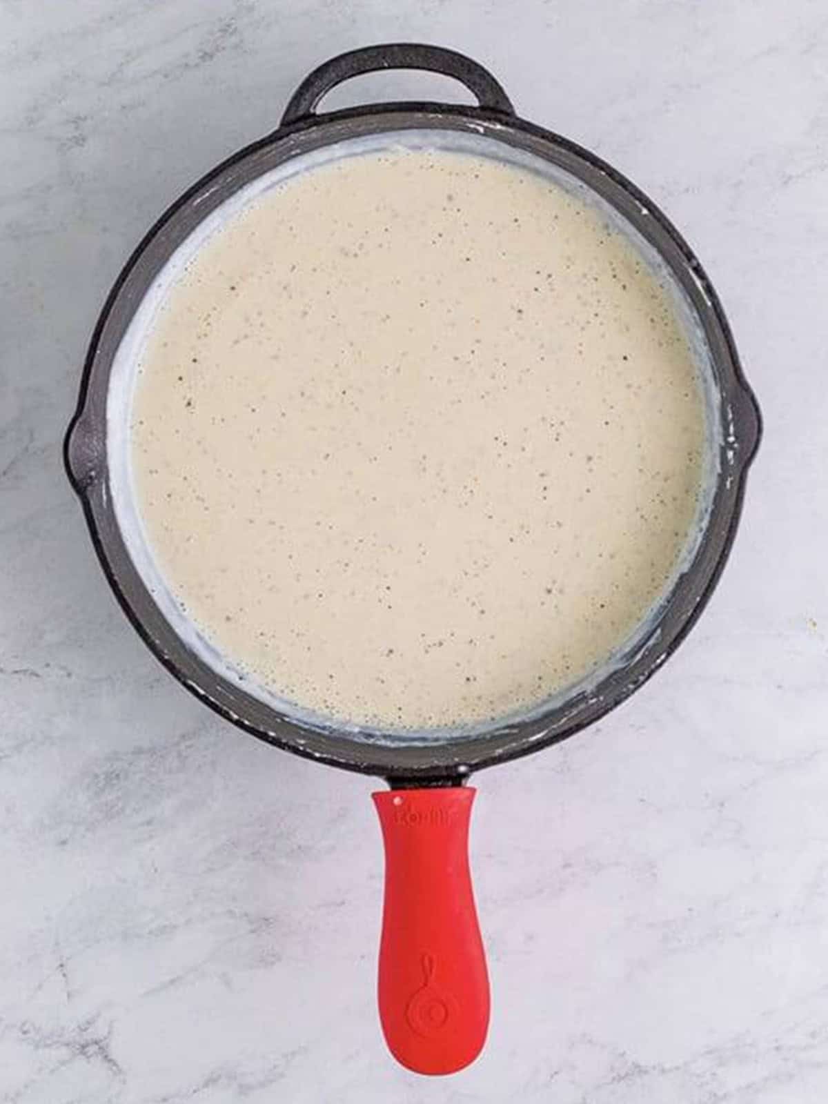 Smooth thickened country gravy simmered in a cast iron skillet for steak fingers.