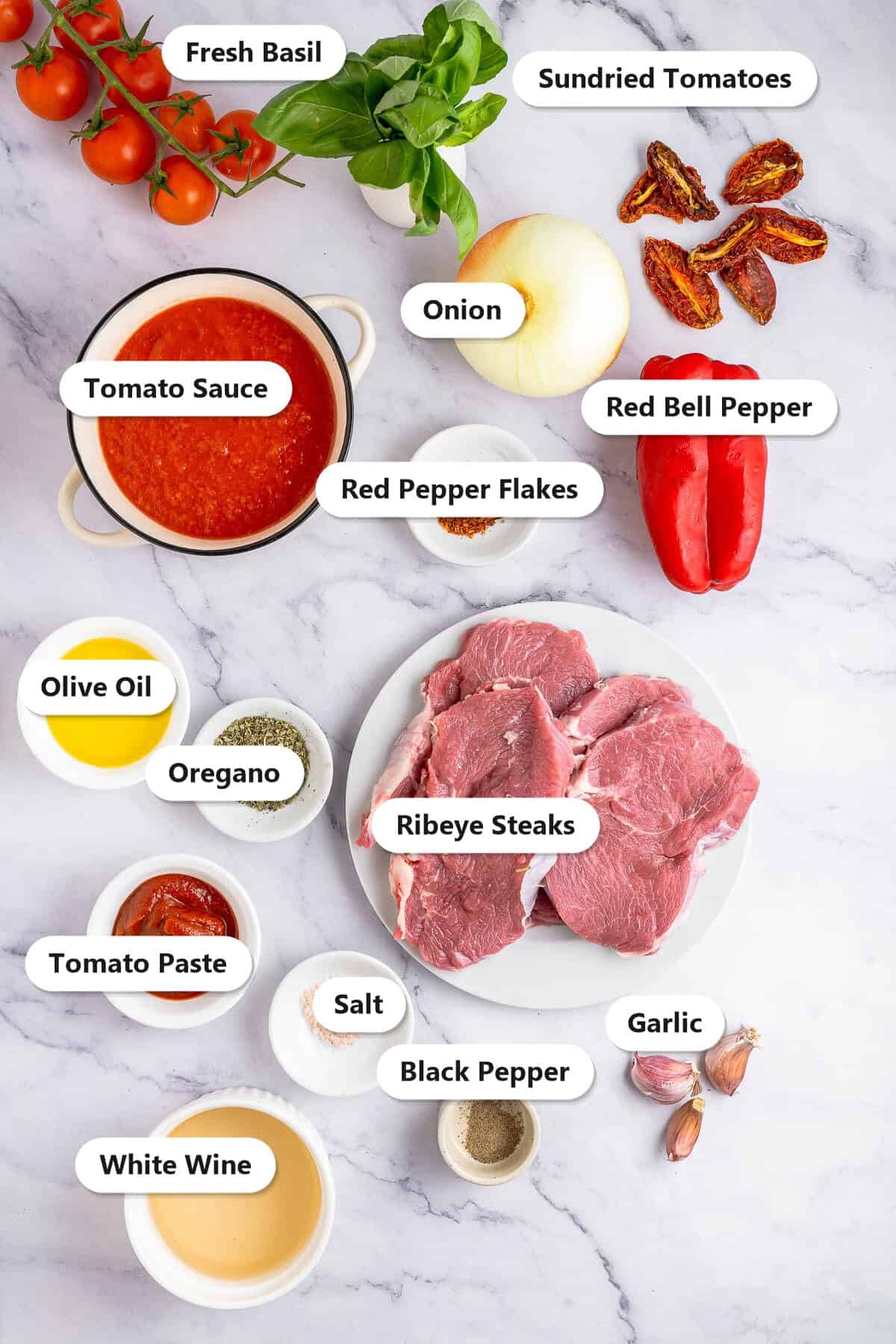 Labeled ingredients to make steak pizzaiola including ribeye steaks, tomato sauce, bell pepper, onion, garlic, white wine, and Italian herbs.