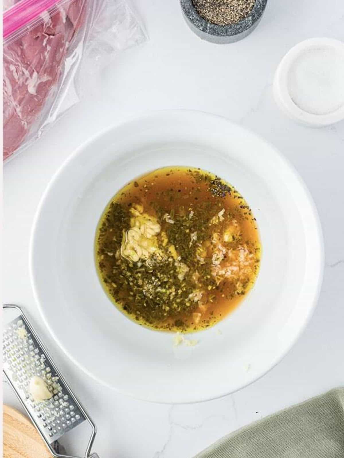 Pesto marinade ingredients combined in a white bowl for grilled pork tenderloin.