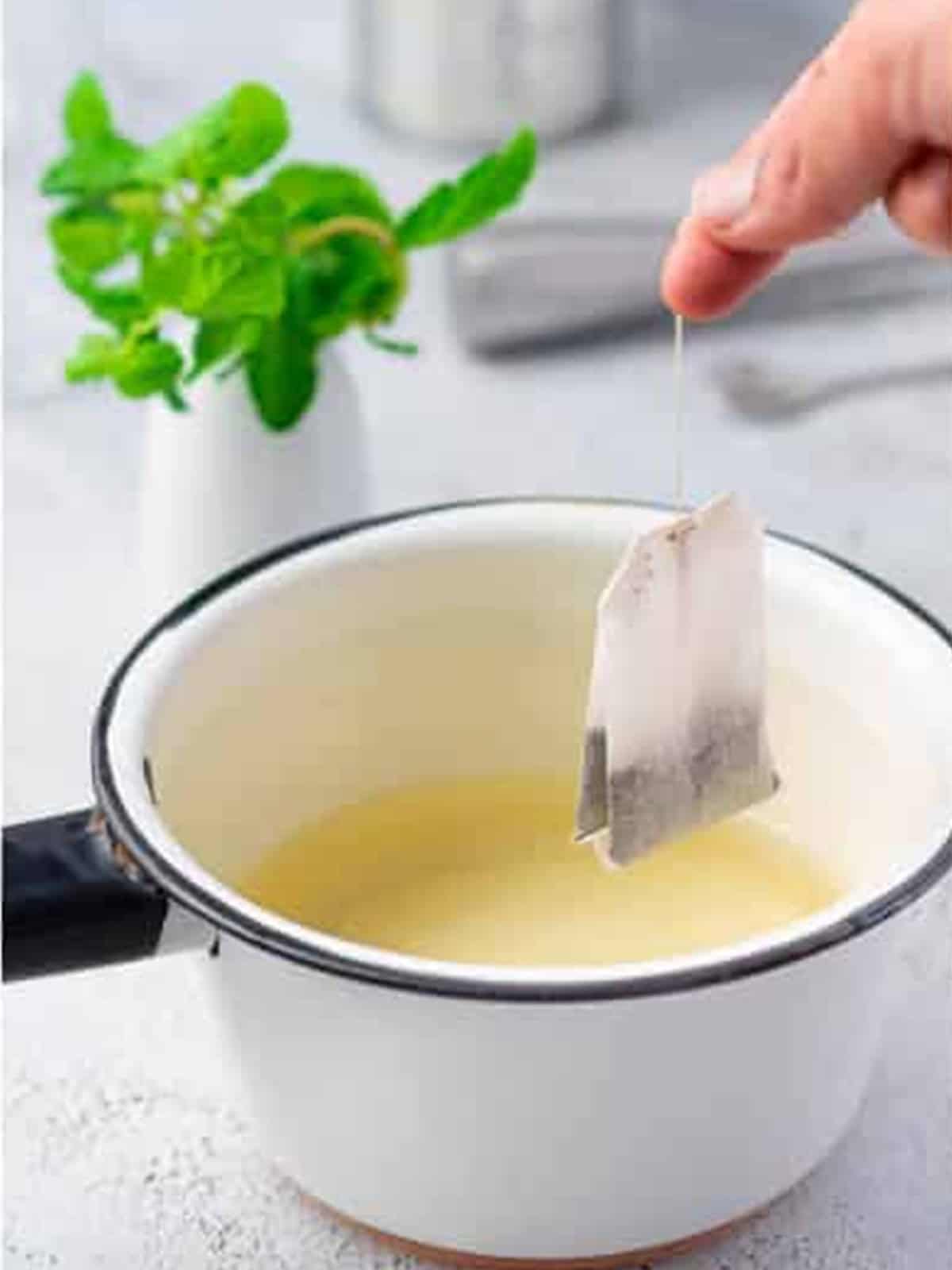 Steeping black tea in sweetened water in a saucepan for peach tea.