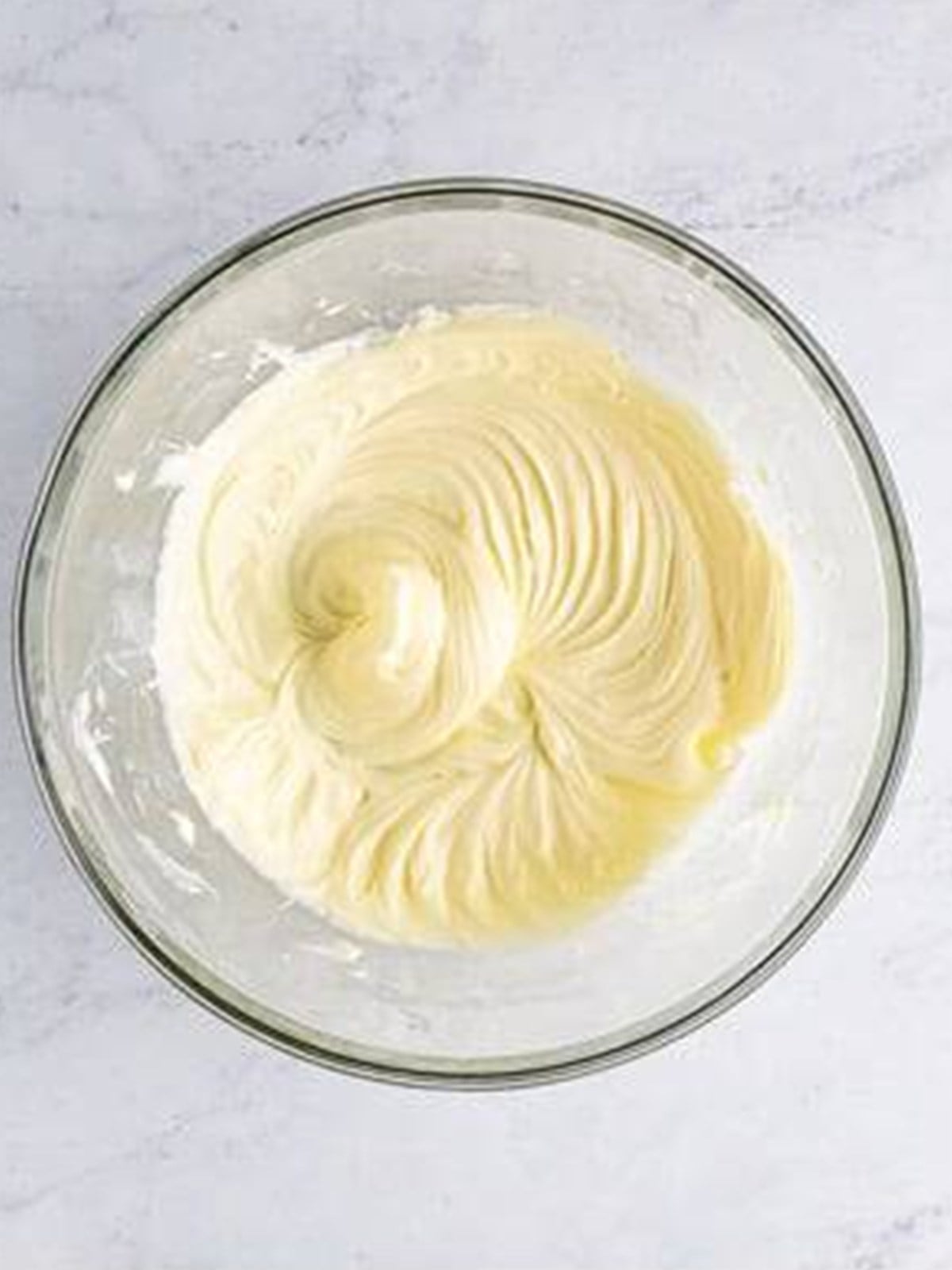 Cream cheese and powdered sugar whipped smooth in a glass bowl.