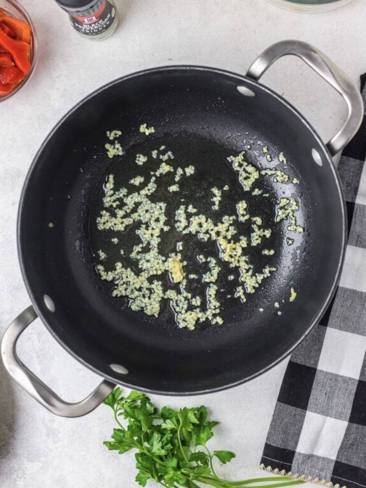 Minced garlic sauteing in olive oil in a large skillet.
