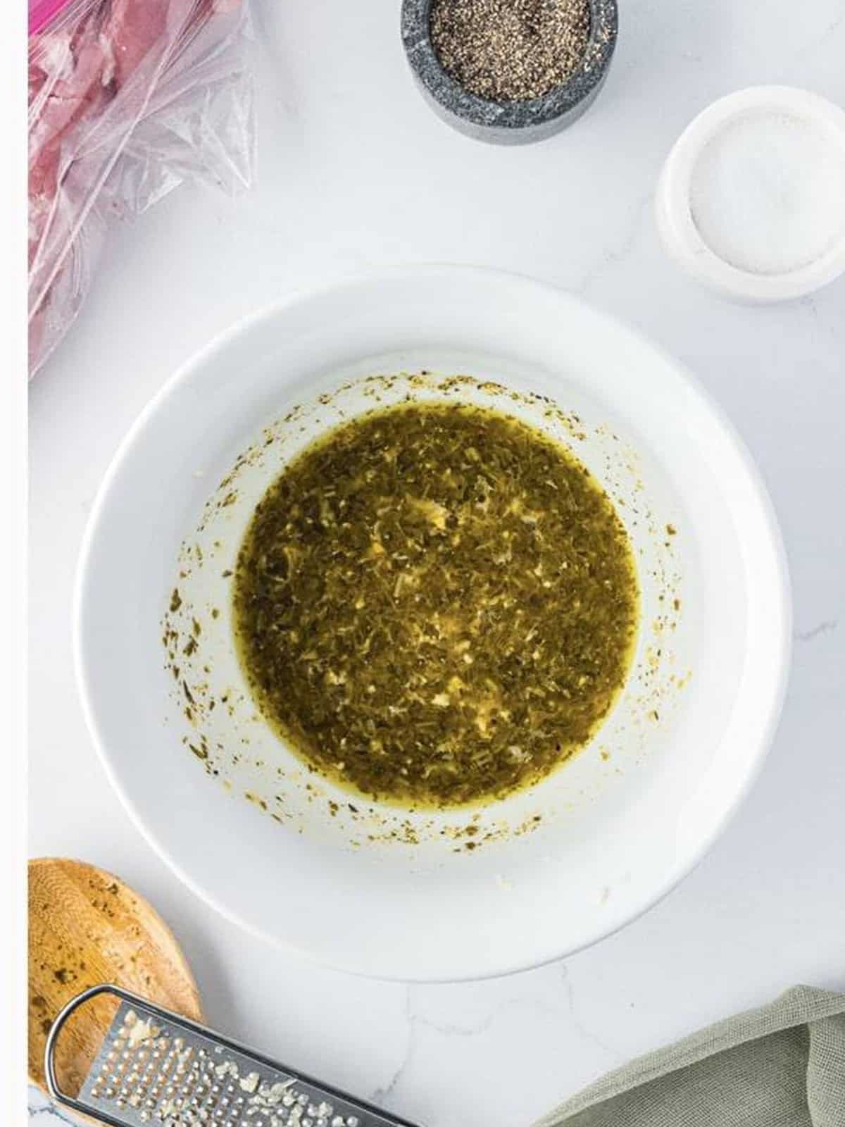 Whisked pesto marinade for grilled pork tenderloin in a white bowl.