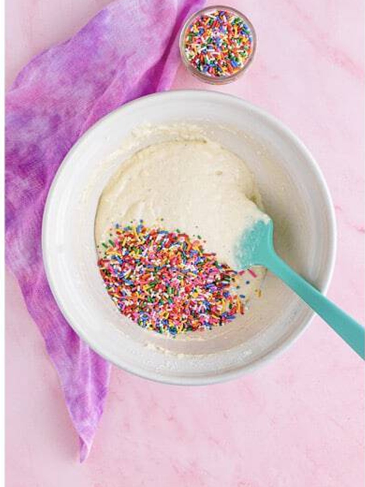 Rainbow sprinkles added to ice cream bread batter in a bowl.