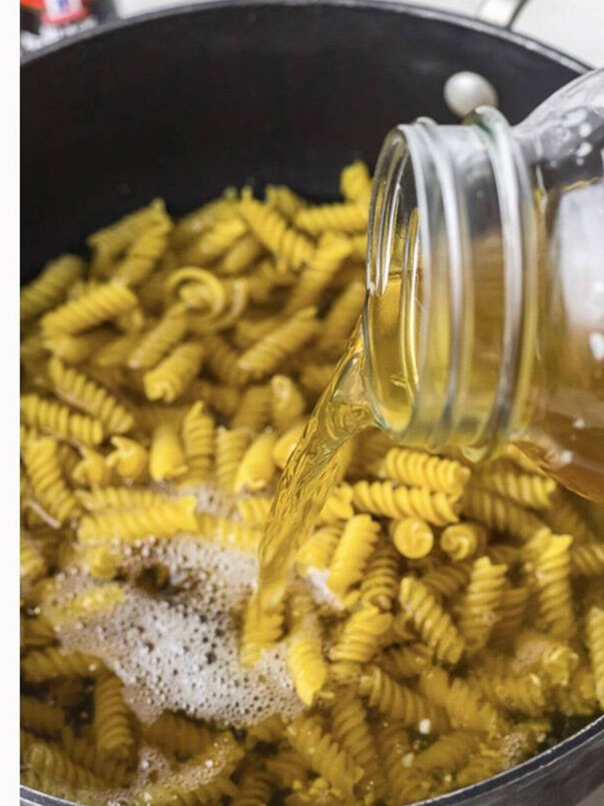Rotini pasta and chicken stock added to the skillet.
