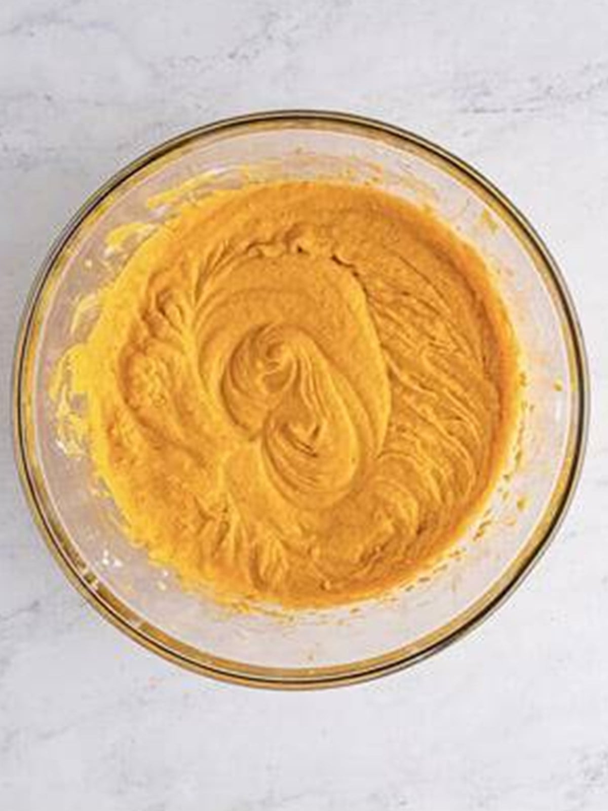 Smooth pumpkin cheesecake filling mixed in a glass bowl.