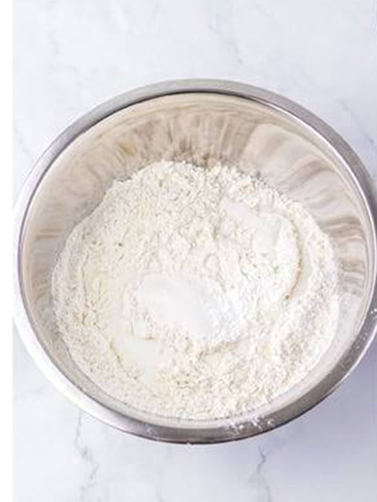 Flour, baking powder, and salt combined with buttermilk in a bowl for dumpling dough.