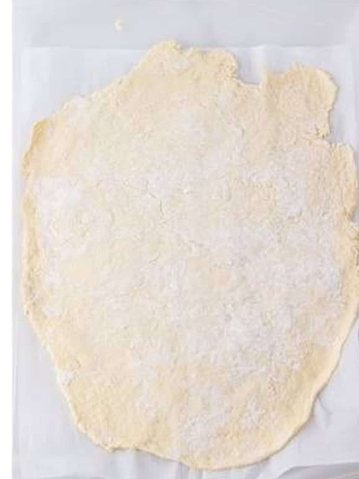 Dumpling dough rolled out thinly on a floured surface.