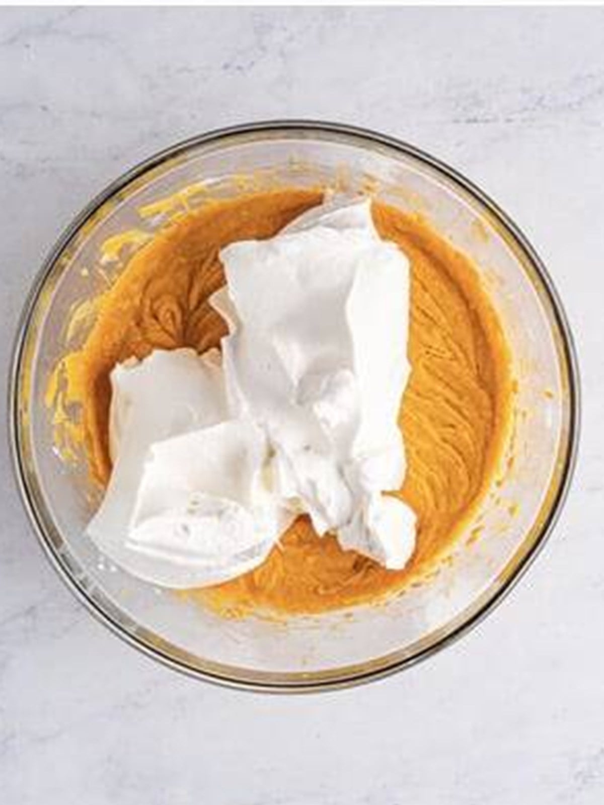 Whipped topping being folded into pumpkin cheesecake filling.