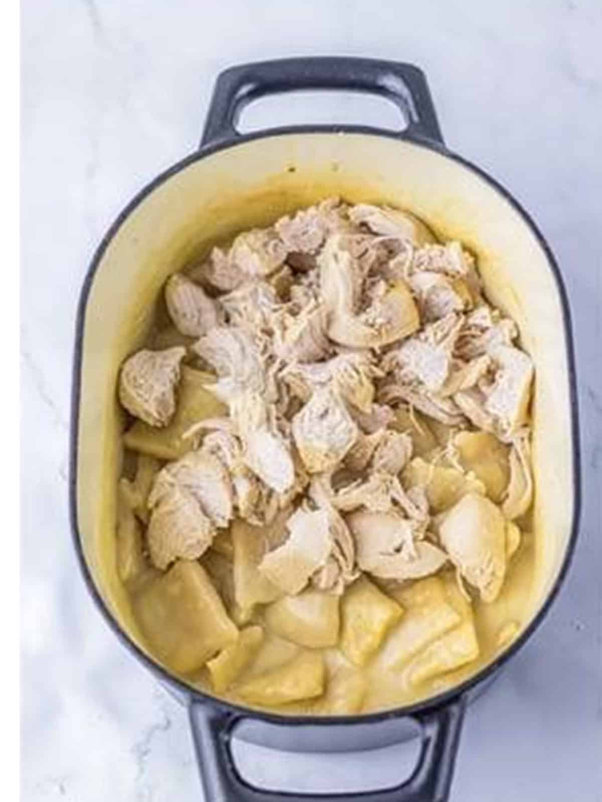 Shredded chicken stirred into the thickened dumpling broth.