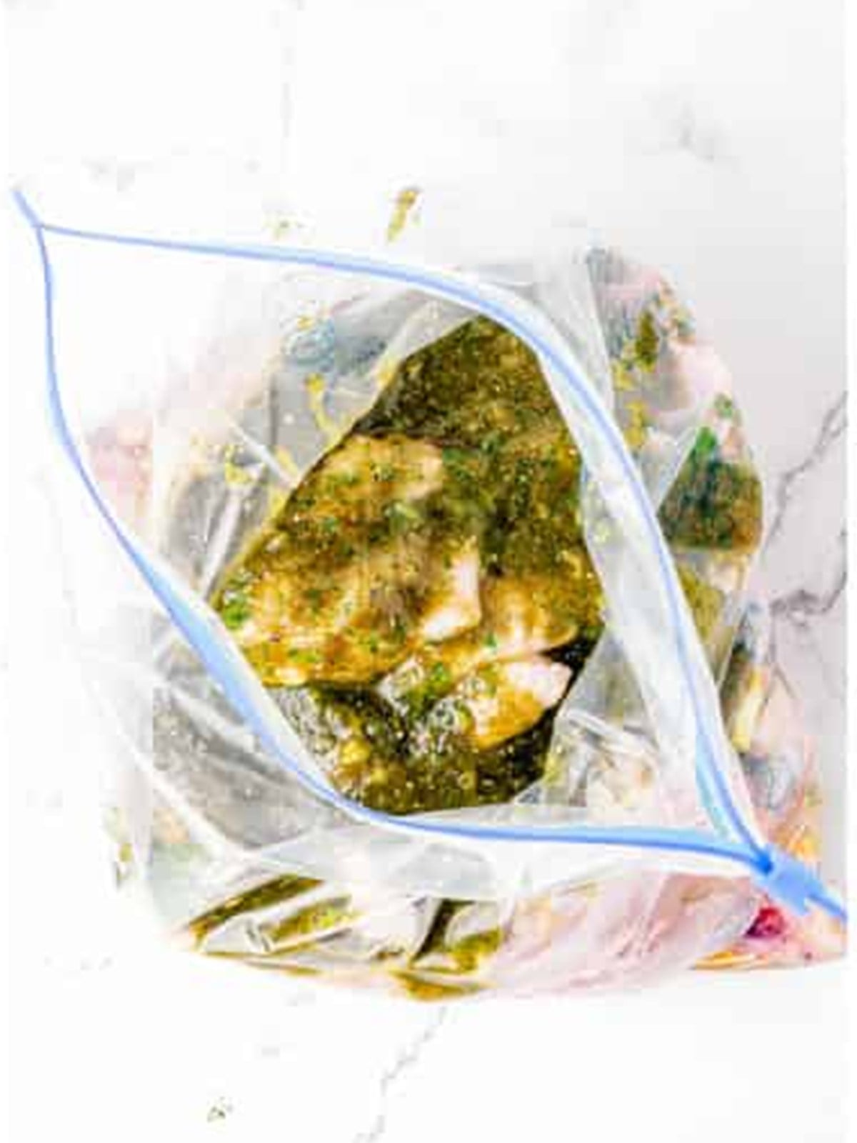 Pouring marinade over raw chicken wings in a plastic bag.