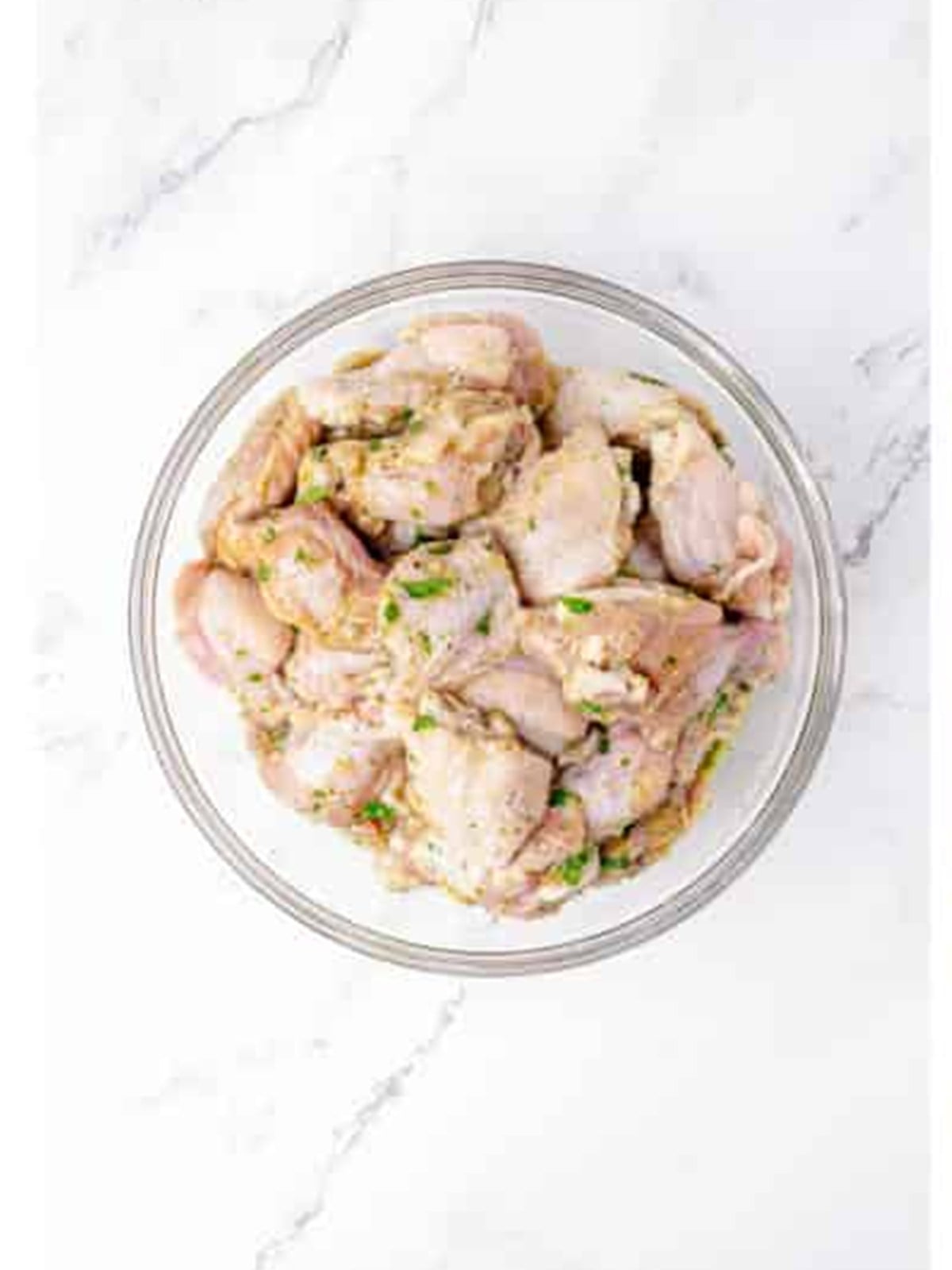 Marinated chicken wings removed from the bag in a glass bowl.