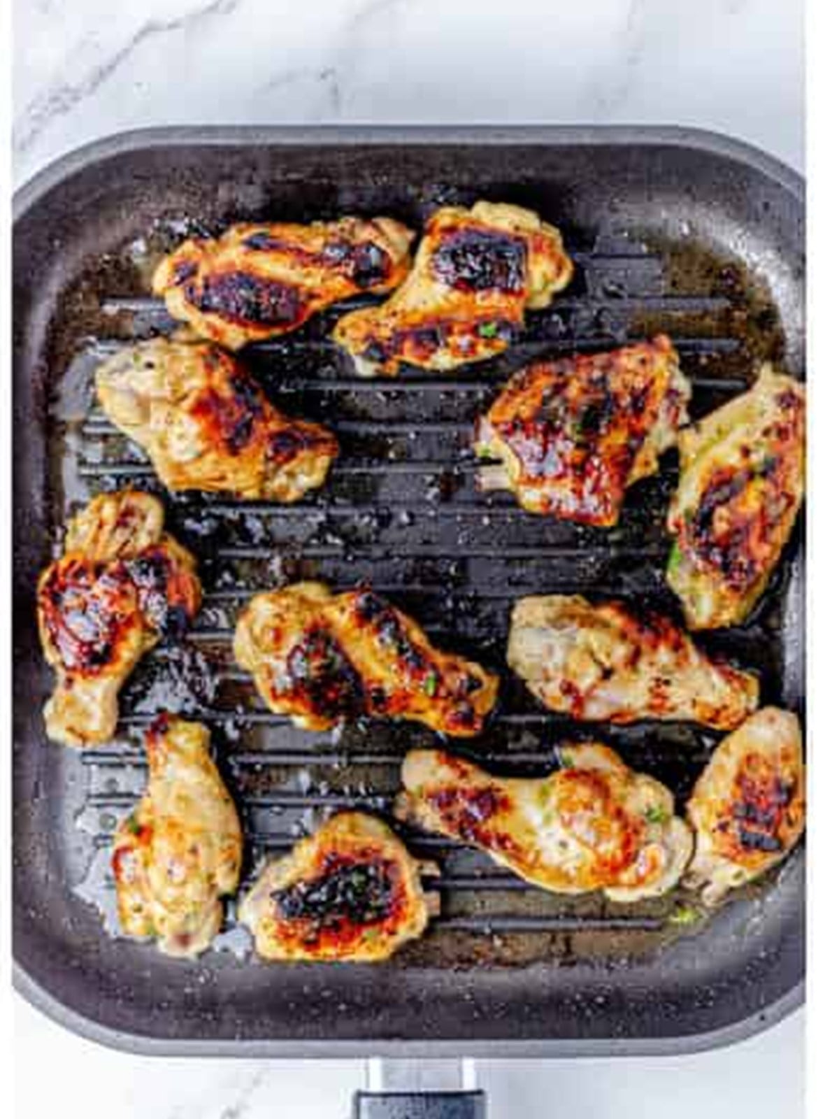 Charred sticky grilled chicken wings on a grill pan.
