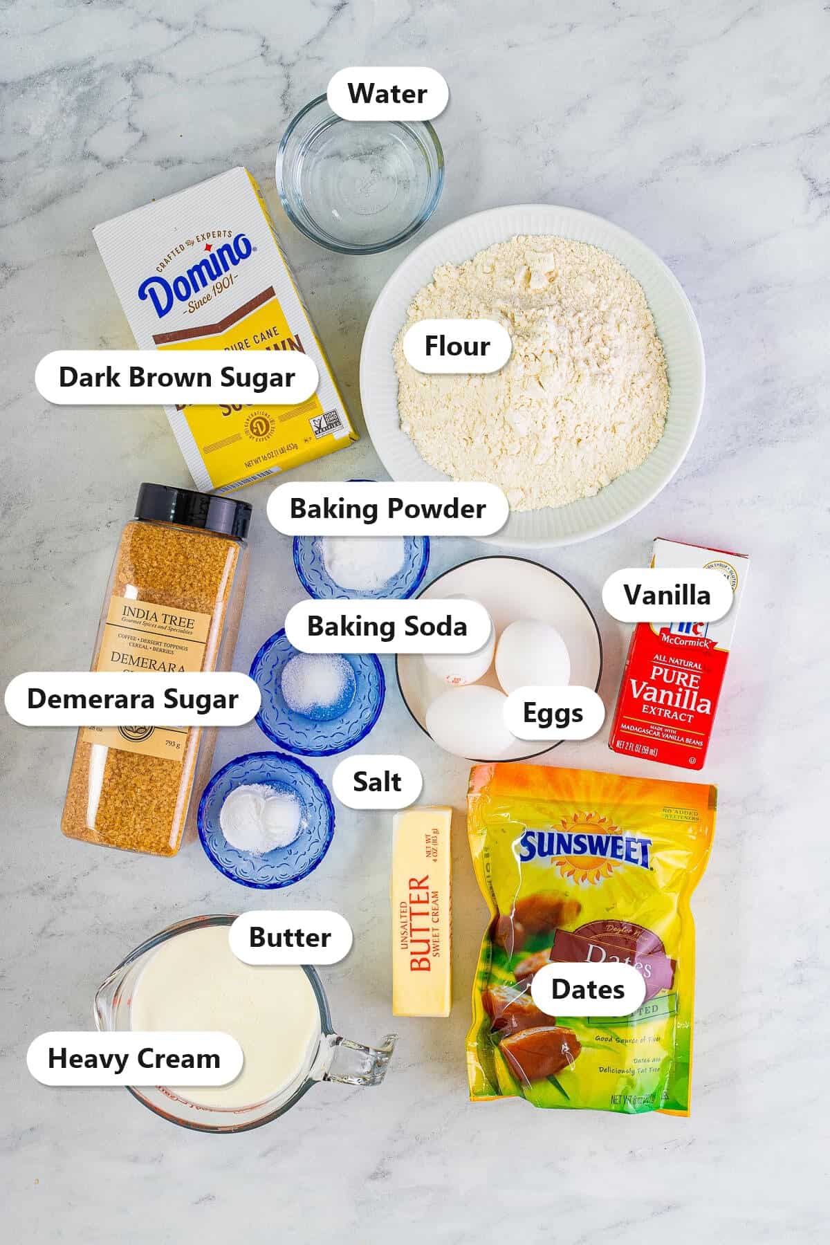 Labeled ingredients for sticky toffee pudding including dates, flour, brown sugar, demerara sugar, butter, heavy cream, eggs, vanilla, and leavening.
