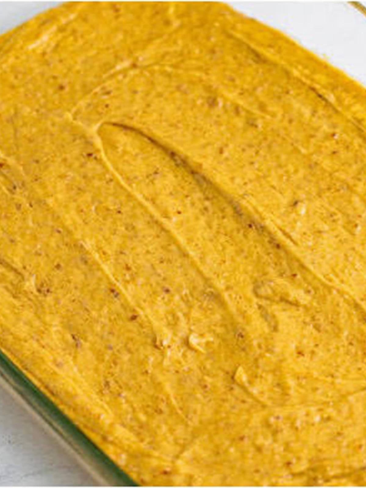 Sticky toffee pudding batter spread in a baking dish before baking.