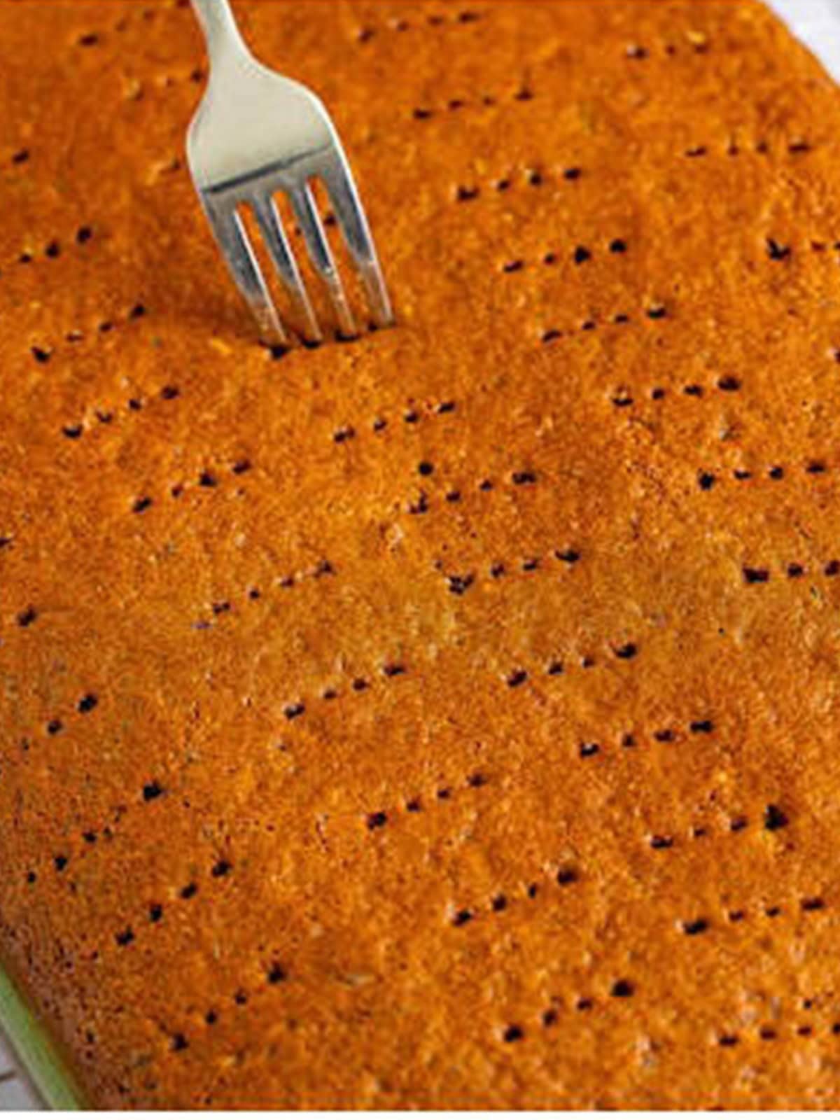 Holes poked all over the baked sticky toffee pudding cake with a fork.