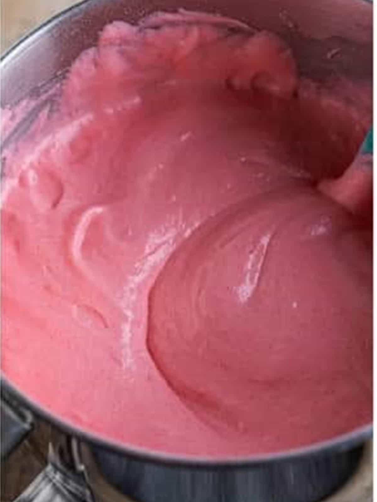 Pink strawberry angel food cake batter folded together in a bowl.
