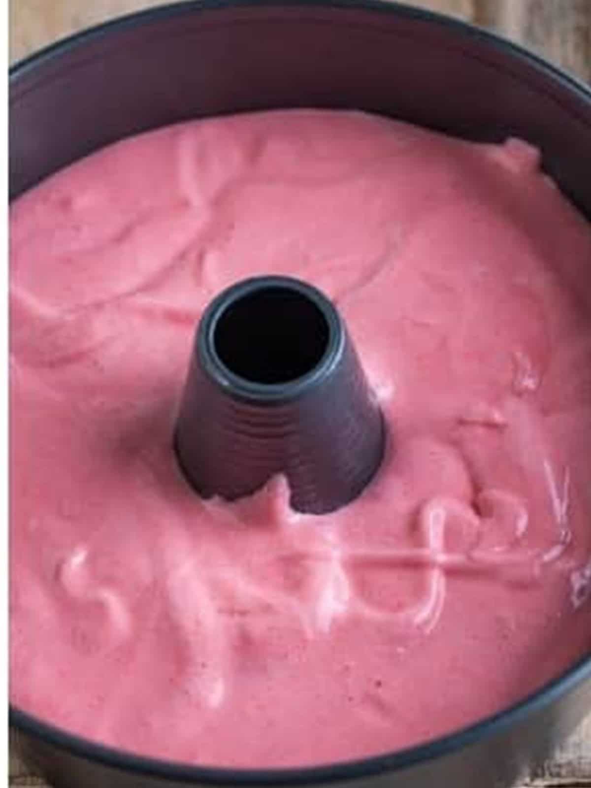 Strawberry angel food cake batter spread in an ungreased tube pan.