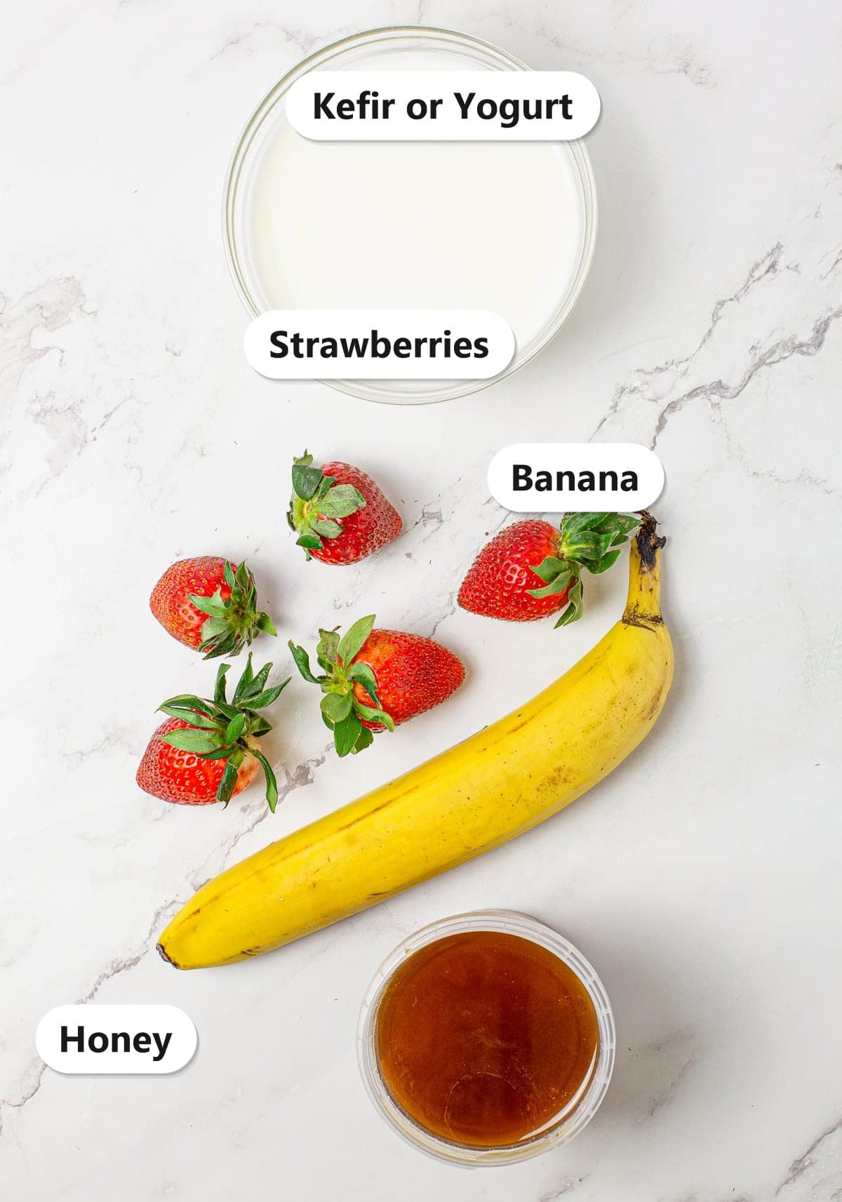 Labeled ingredients for a strawberry banana smoothie including kefir or yogurt, strawberries, banana, and honey.