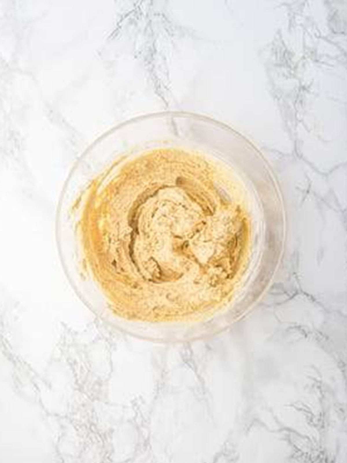 Butter and brown sugar creamed together in a glass bowl for strawberry cookies.