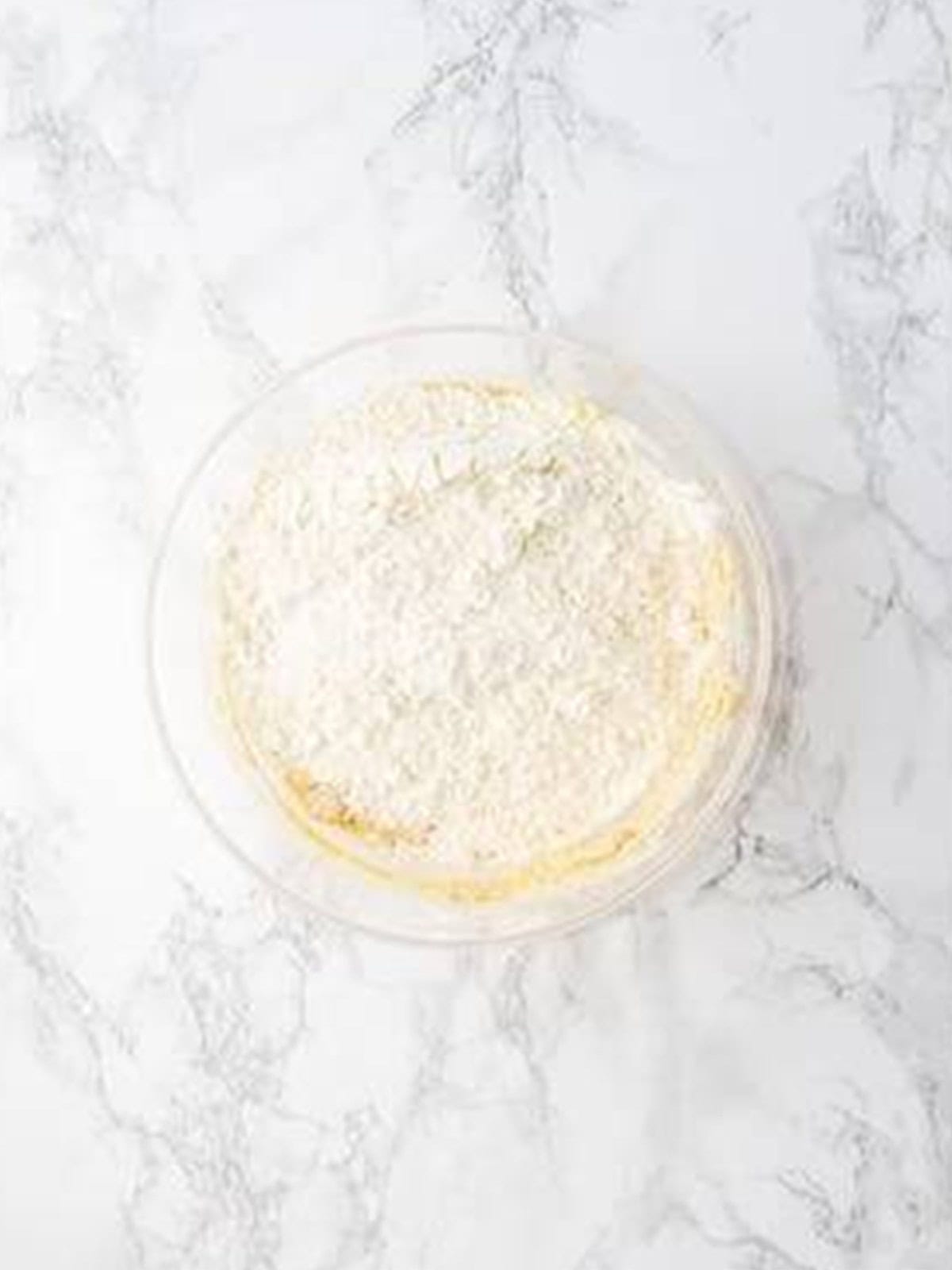 Flour added to the strawberry cookie dough in a glass bowl.