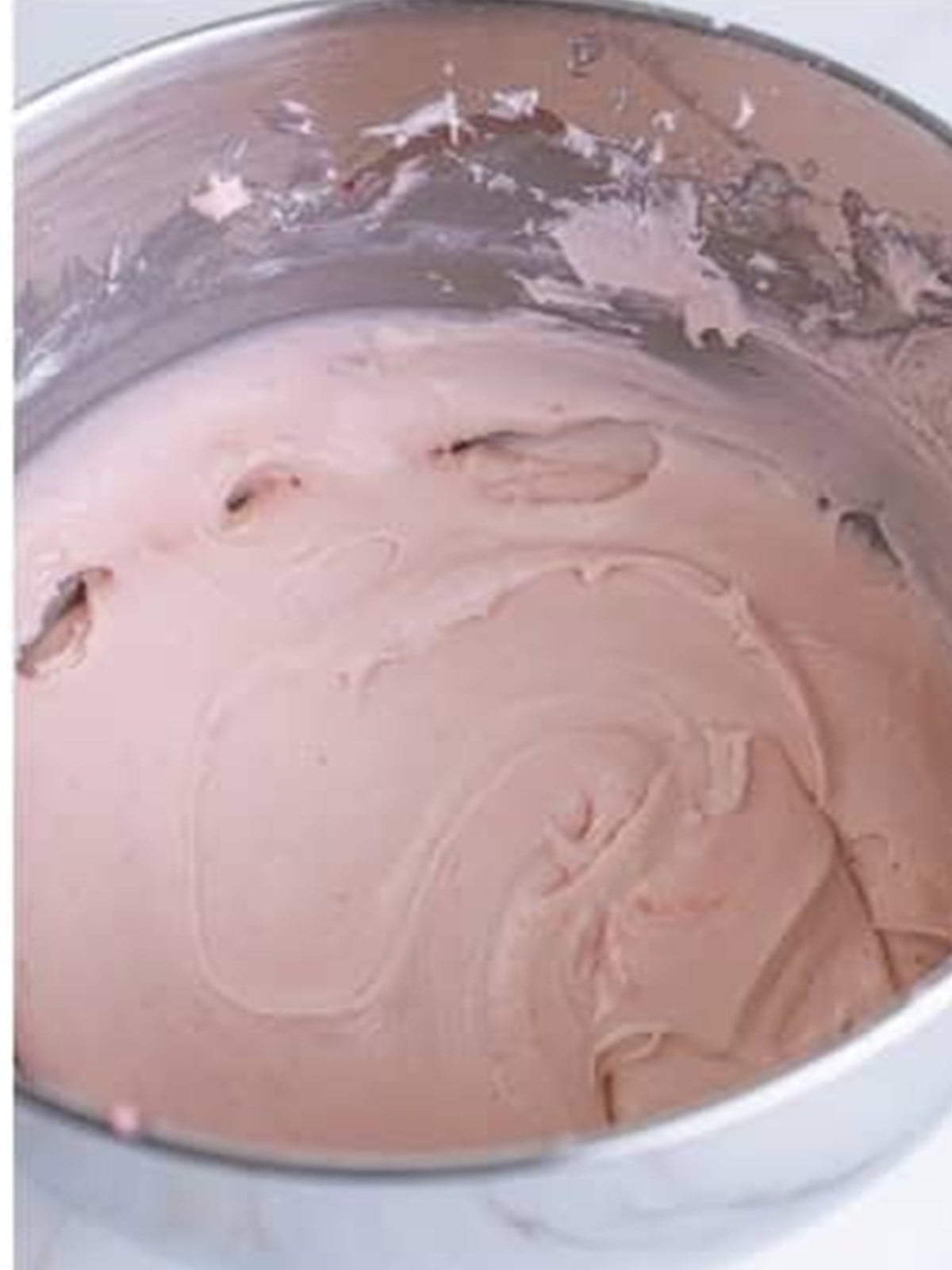 Finished smooth pink strawberry cream cheese frosting in a mixing bowl.