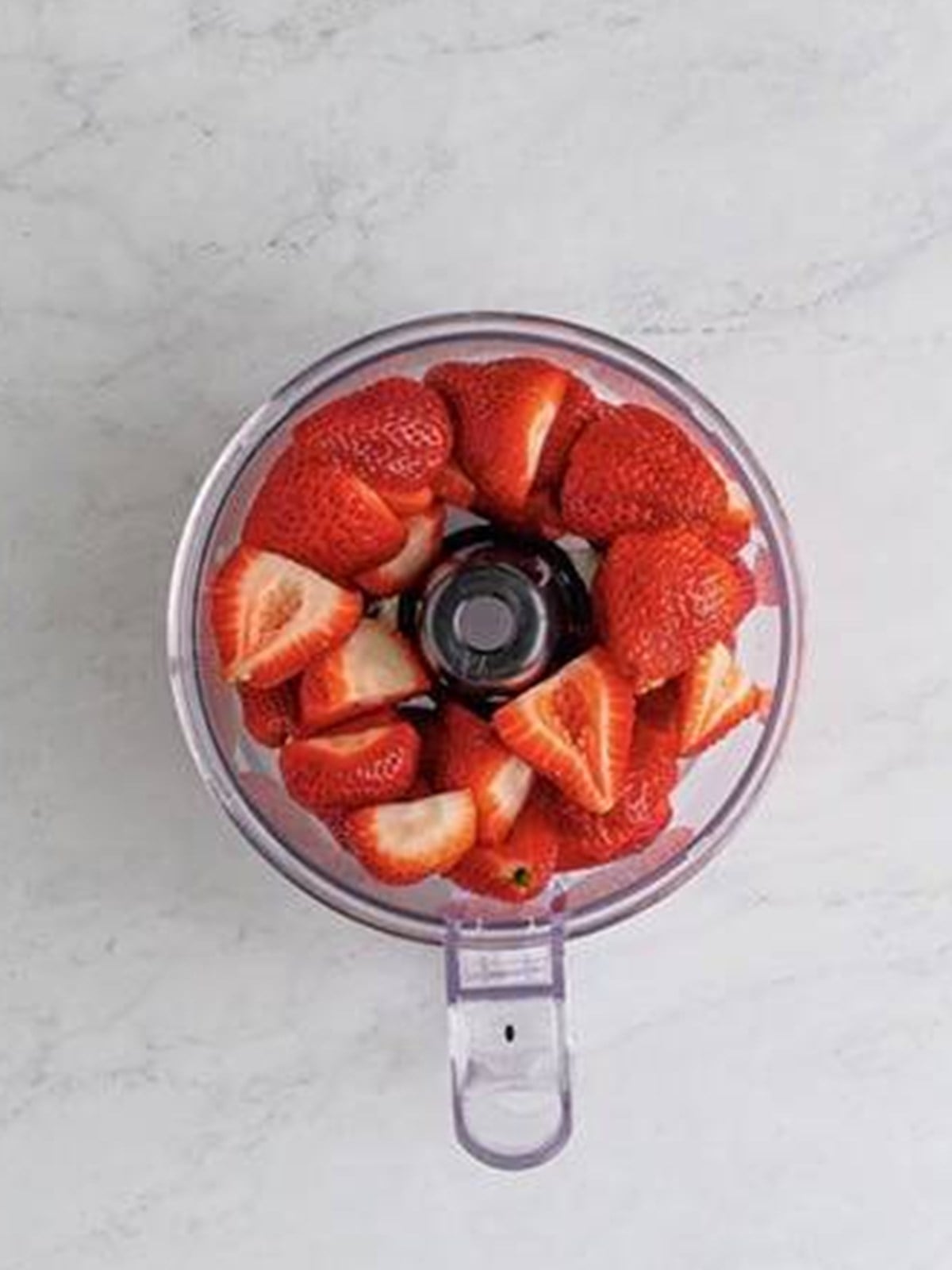 Fresh strawberries in a food processor for strawberry freezer jam.