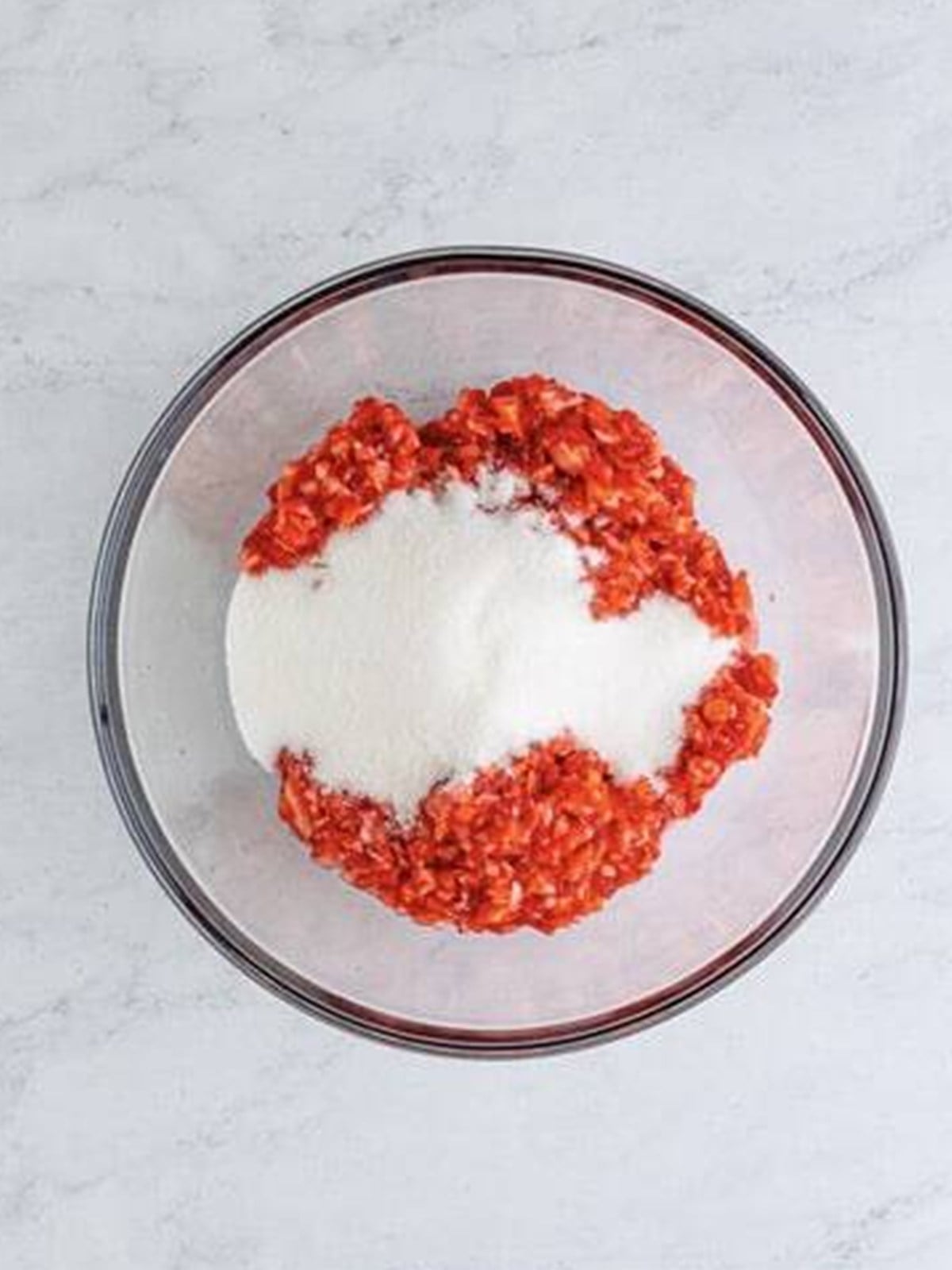 Adding sugar to crushed strawberries for freezer jam.