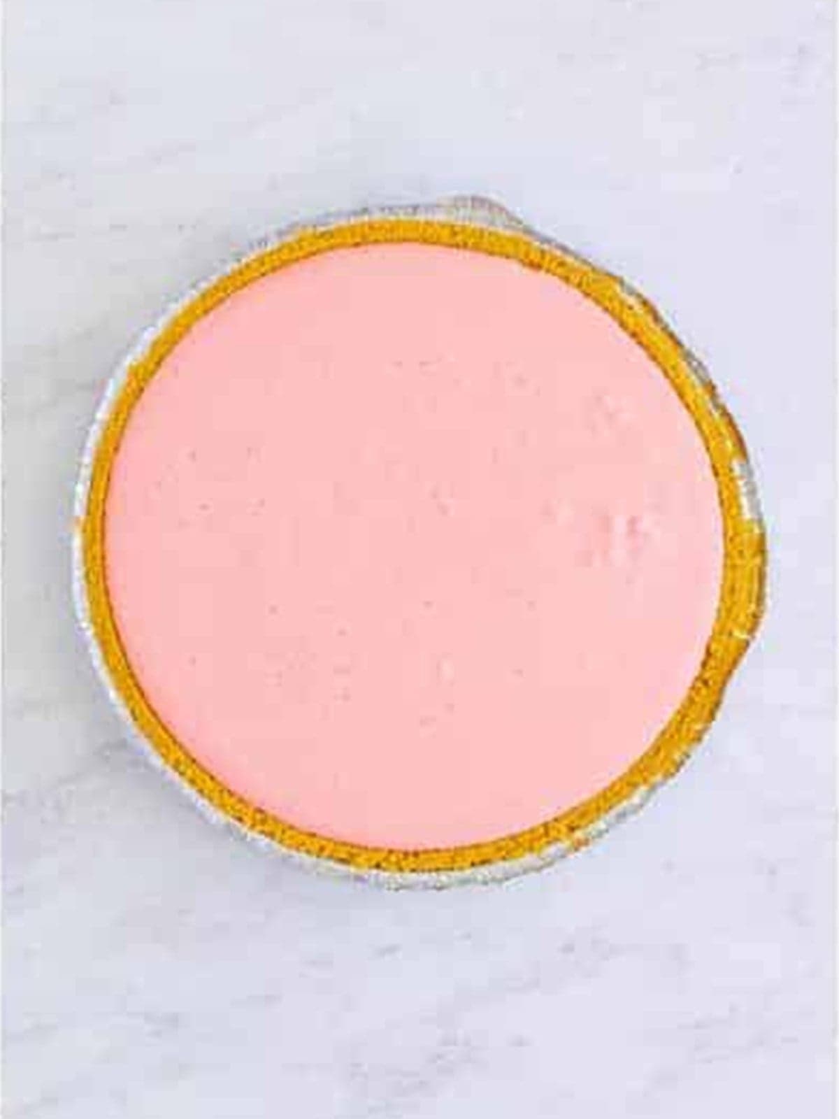 Strawberry jello filling smoothed into a graham cracker crust.