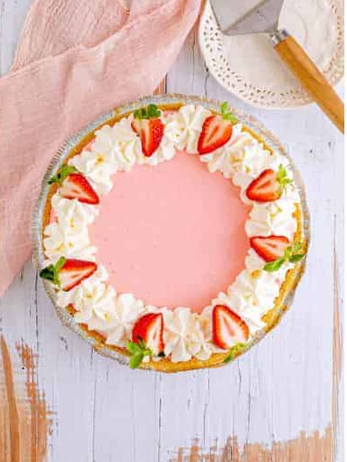 Finished strawberry jello pie garnished with whipped cream and fresh strawberries.