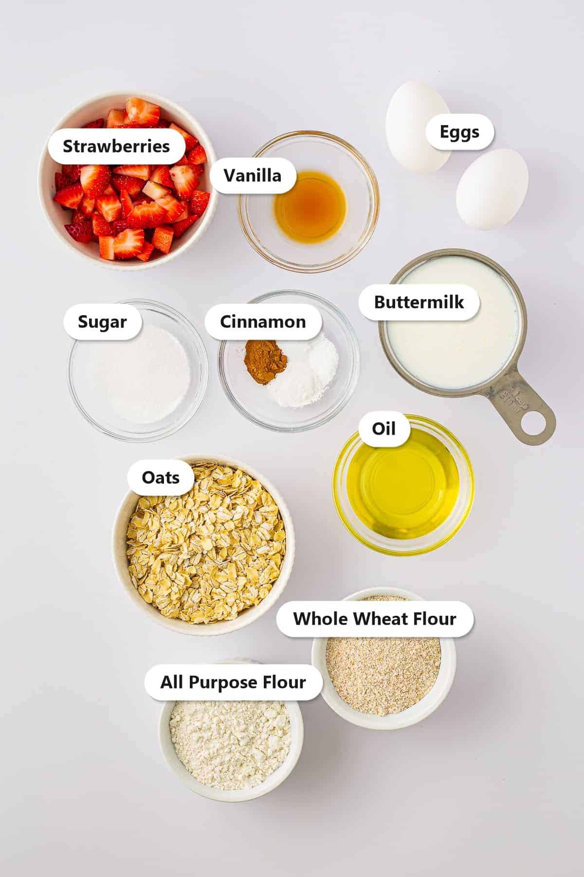 Labeled ingredients for strawberry oatmeal pancakes including oats, buttermilk, eggs, flour, strawberries, cinnamon, sugar, and oil.
