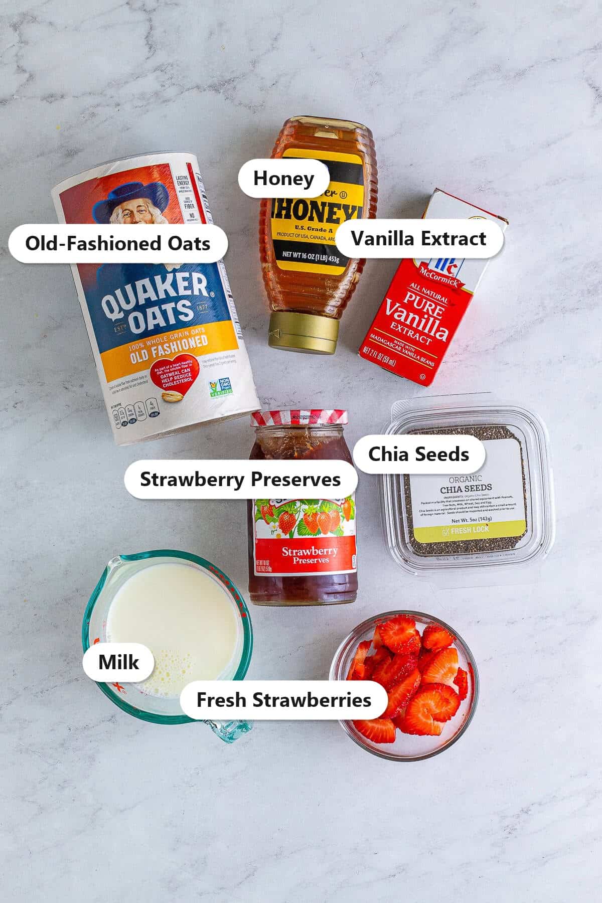 Labeled ingredients for strawberry overnight oats including old-fashioned oats, milk, honey, strawberry preserves, chia seeds, vanilla, and fresh strawberries.