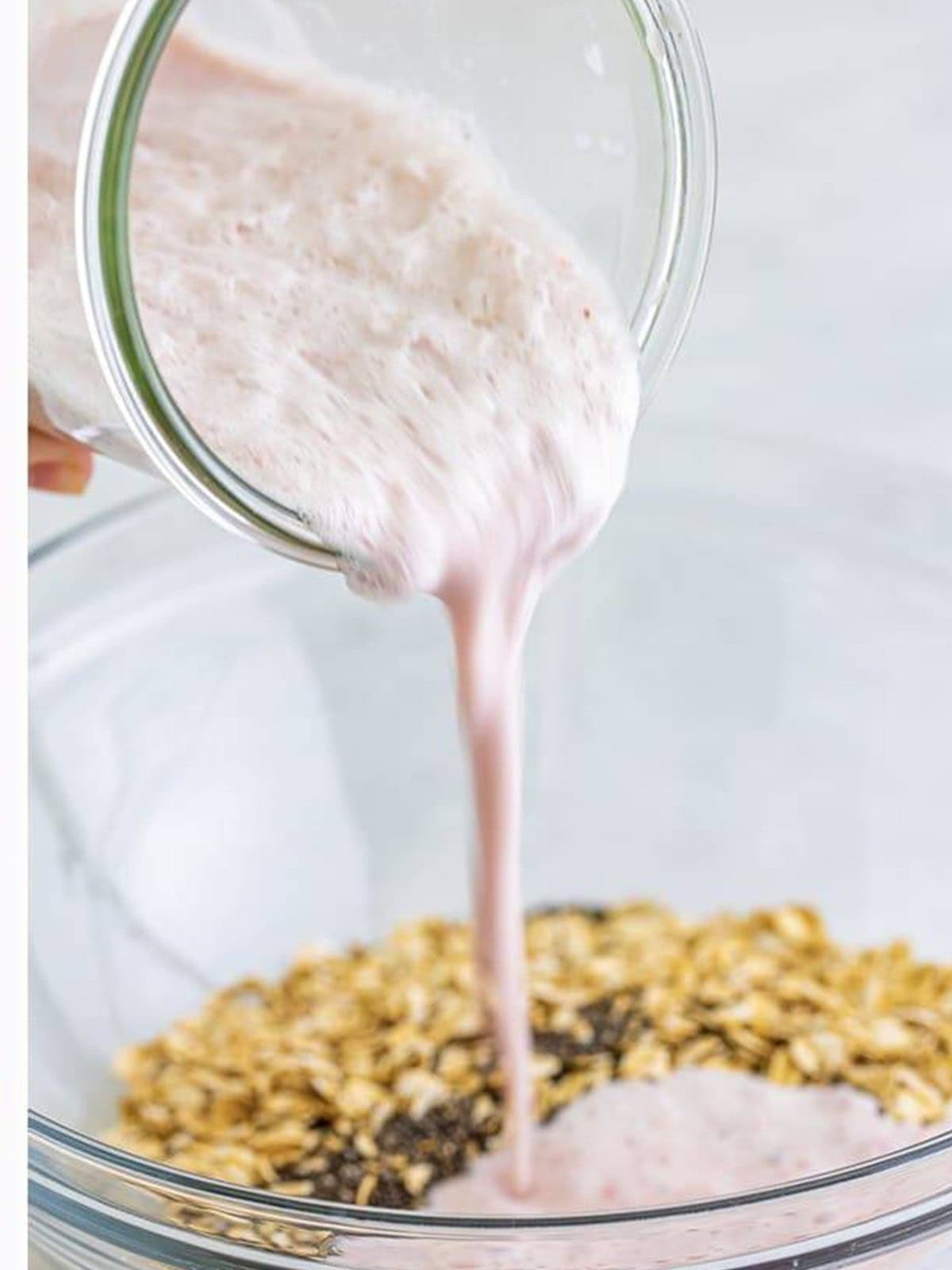 Strawberry milk mixture poured over oats and chia seeds in a bowl.