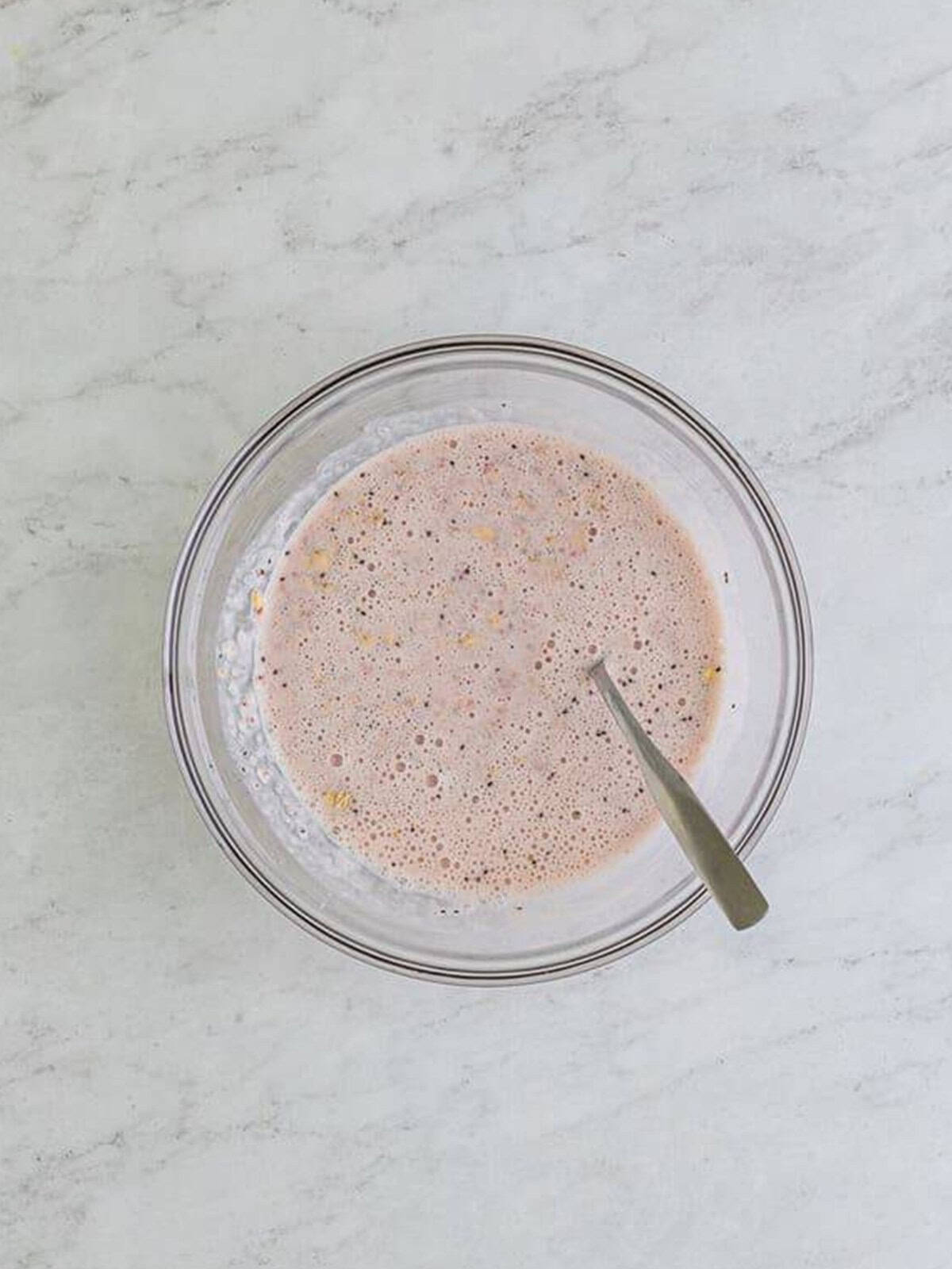 Stirring the strawberry oat mixture together in a glass bowl.