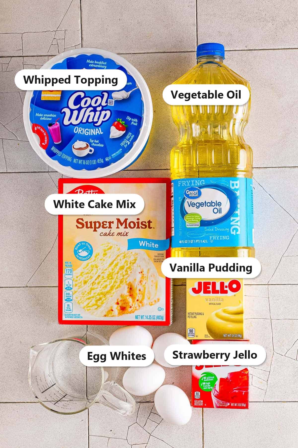 Labeled strawberry poke cake ingredients including white cake mix, strawberry jello, vanilla pudding, whipped topping, and eggs.