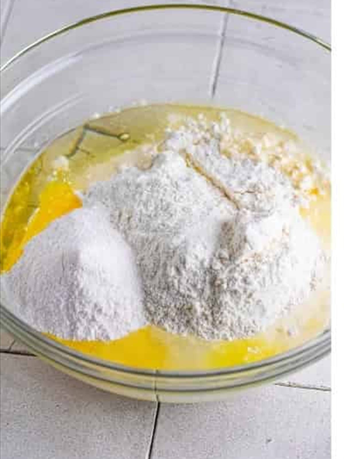 Cake mix, pudding, and wet ingredients in a bowl for strawberry poke cake.