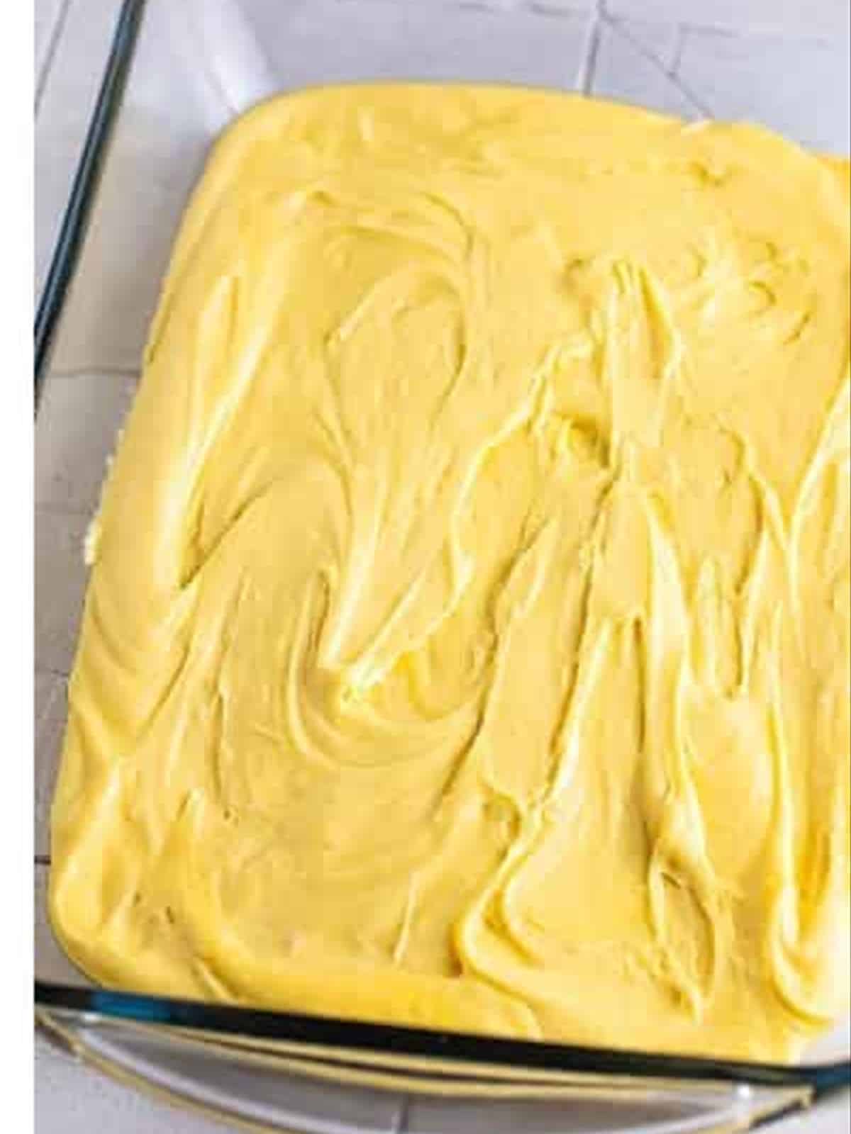 Cake batter spread in a baking dish for strawberry poke cake.