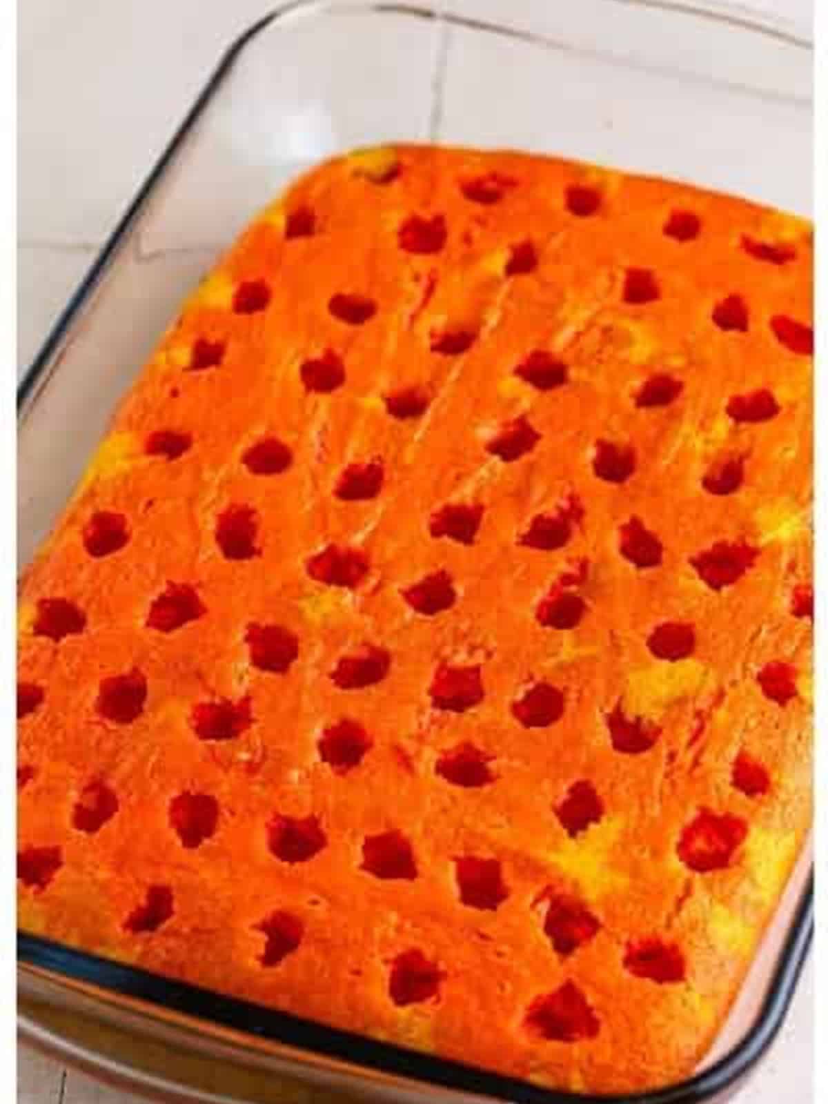 Strawberry jello poured over the poked cake.