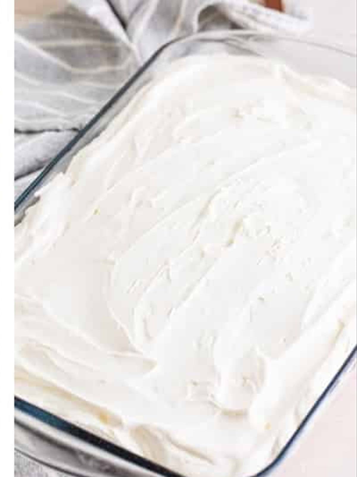 Whipped topping spread over the strawberry poke cake.