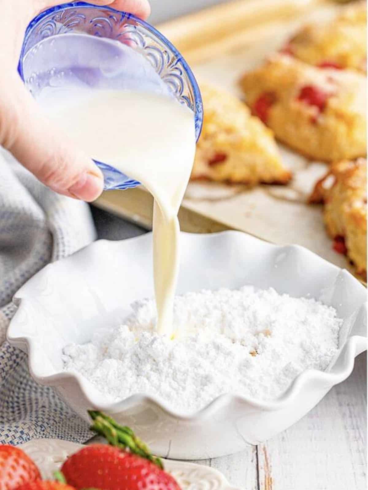 Making the vanilla glaze by pouring cream into powdered sugar.