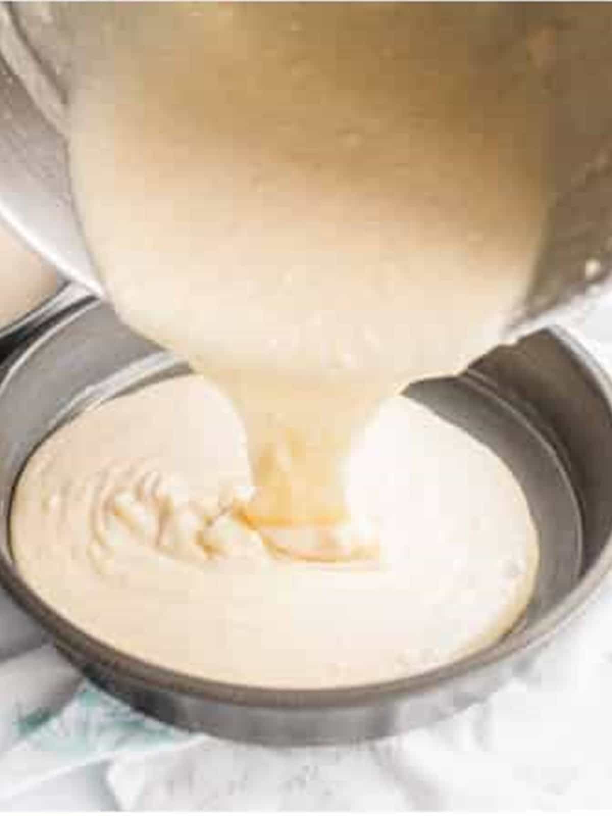 Light cake batter poured into a round cake pan for the cake layers.